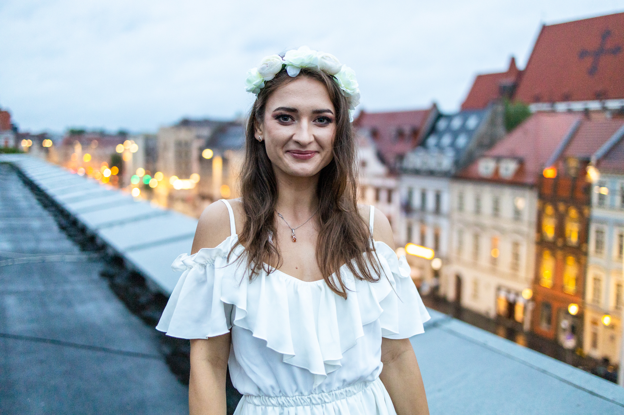 Panna młoda uśmiechająca się do zdjęcia na tle wieczornego miasta– zdjęcie z wieczoru panieńskiego, pełne emocji i radości.